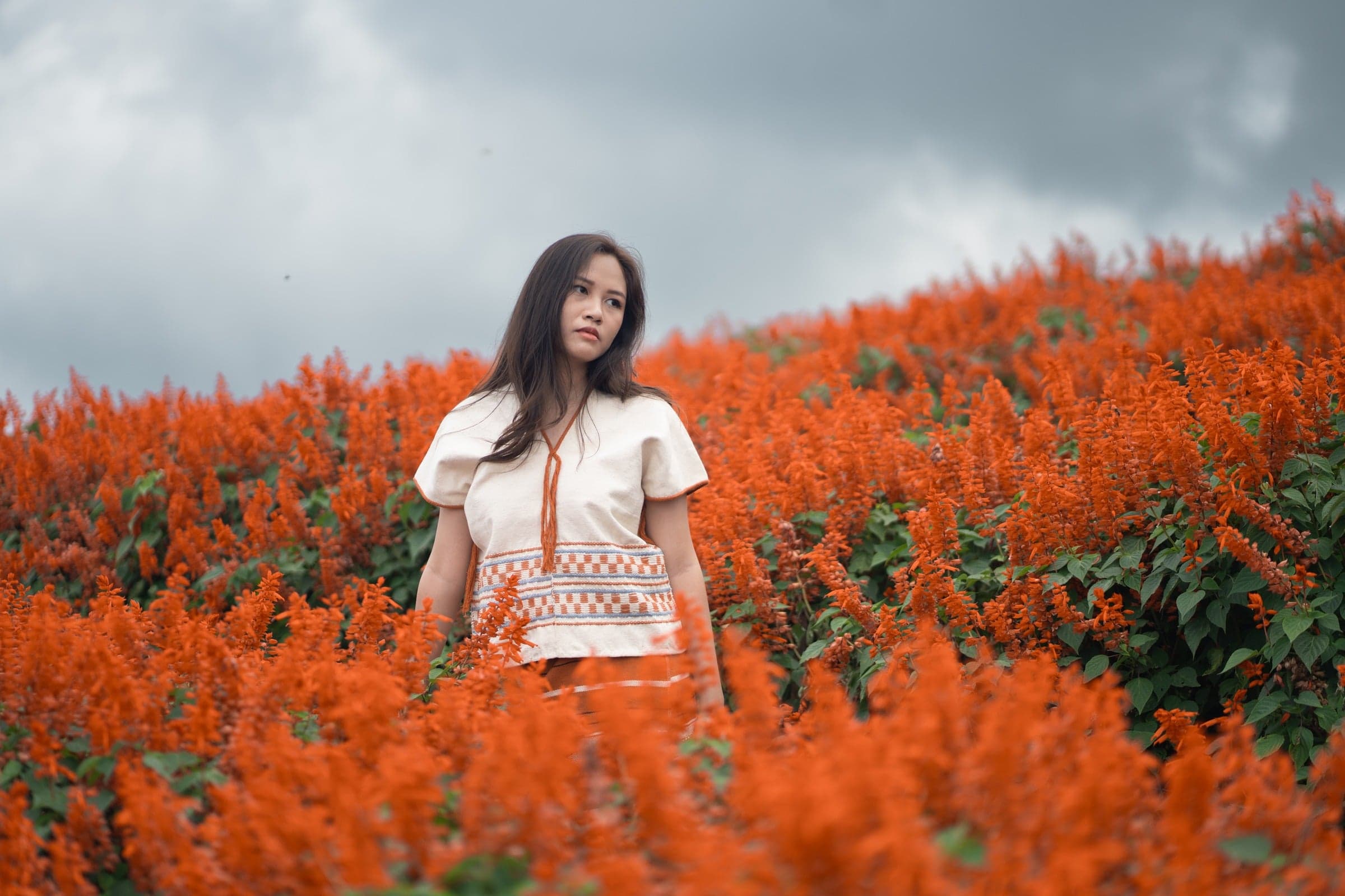 Woman in field of orange flowers wearing linen garment
